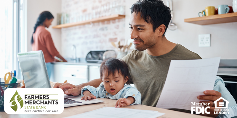 Father financially planning with a laptop at a table with his child on his lap