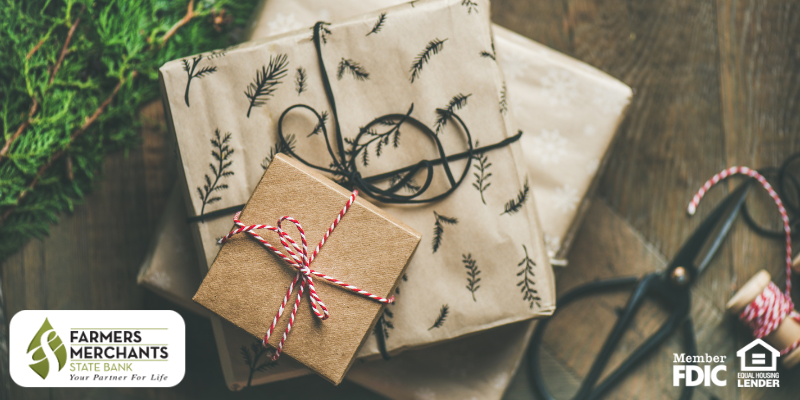 Stack of gifts with greenery on the left and scissors and twine on the right